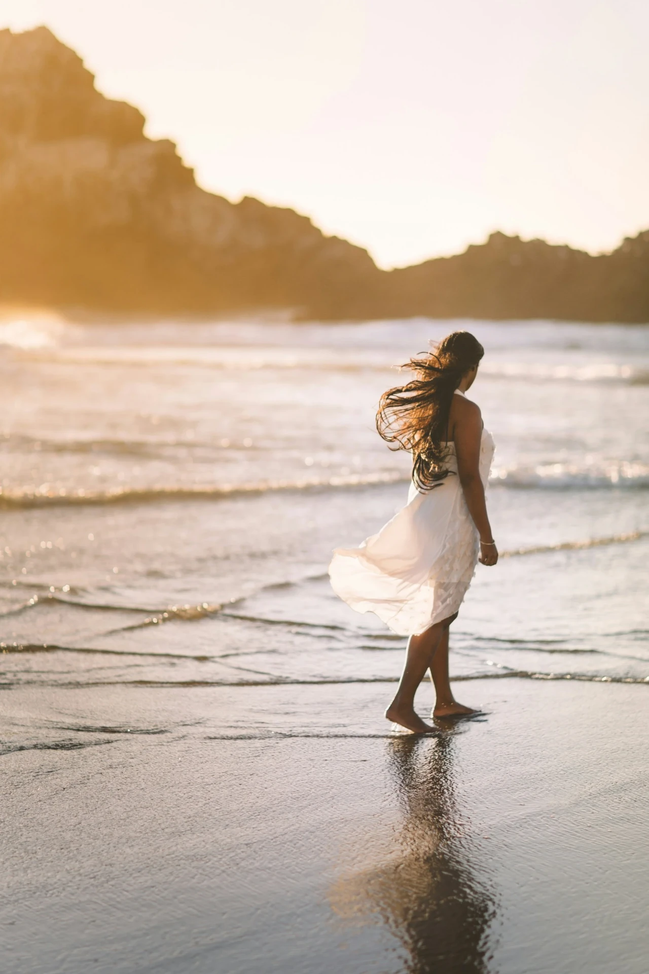 Woman walking barefoot at the ocean's edge