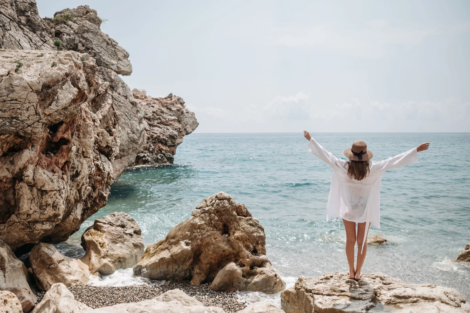 Woman with arms open by the sea in Lisbon